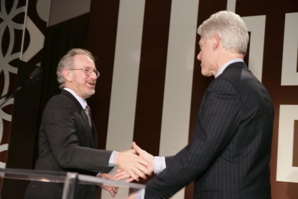 Two men in suits shaking hands at a business meeting.