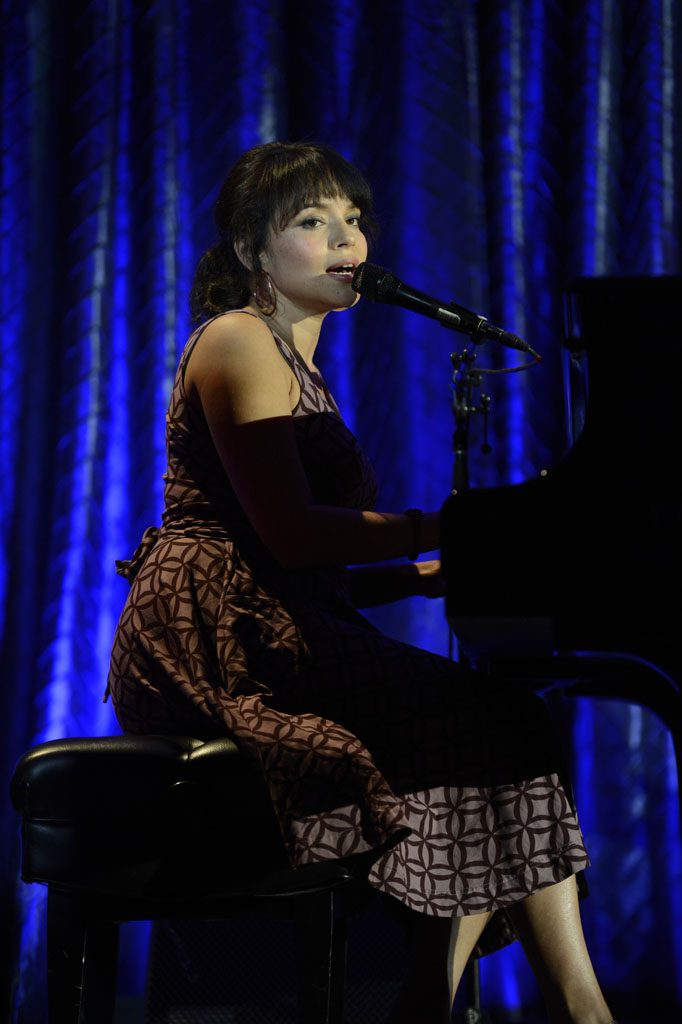 A woman sitting at a piano with a microphone.