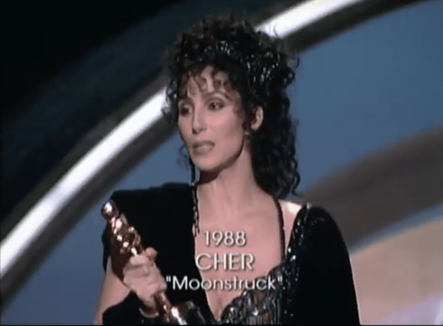 A woman holding an award in front of a microphone.