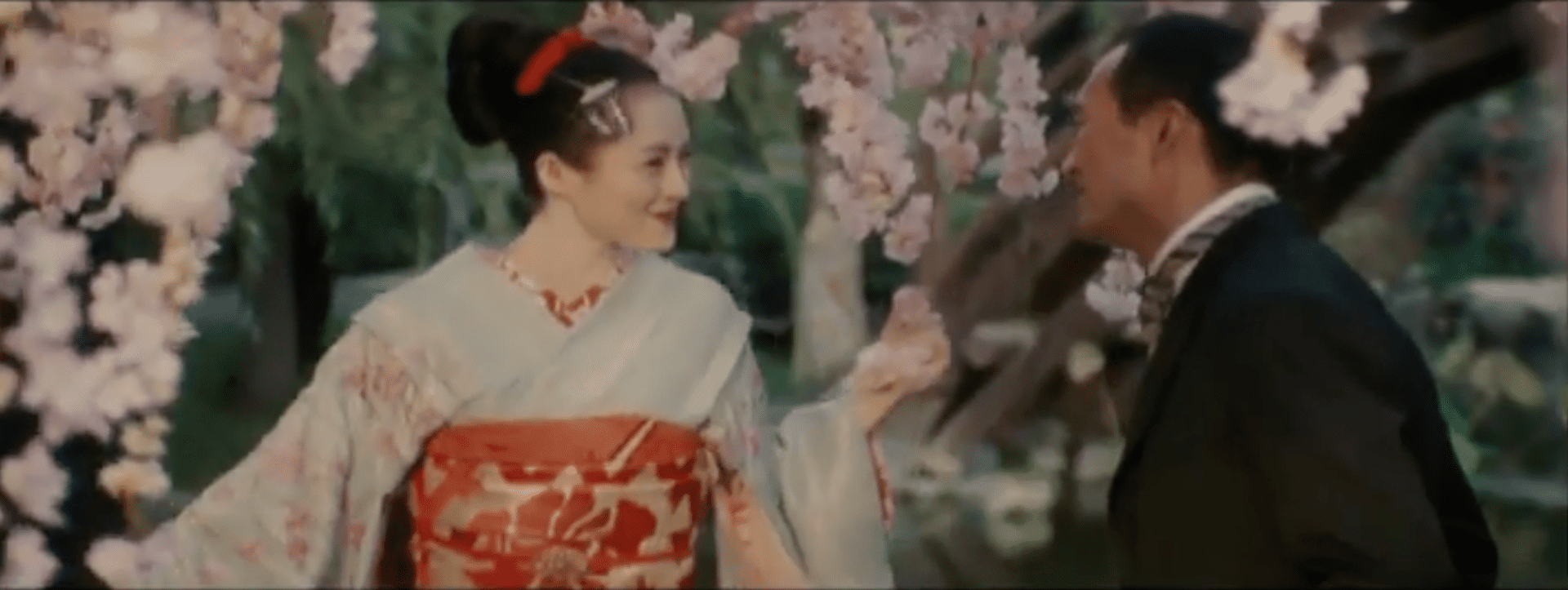 A woman in traditional japanese clothing holding flowers.